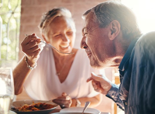 Couple smiling while eating meal together