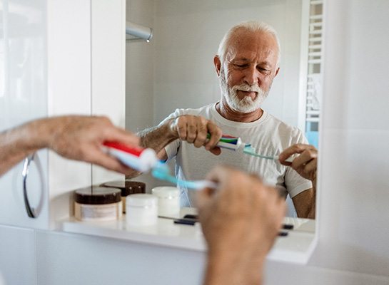 Senior man putting toothpaste on toothbrush