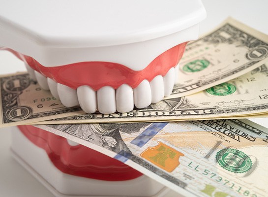 A fake set of teeth biting money