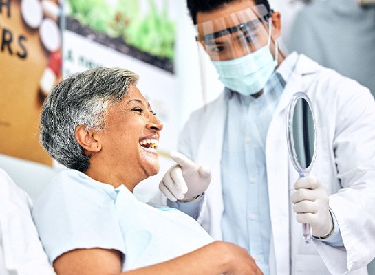 Dentist pointing to woman's smile in treatment chair