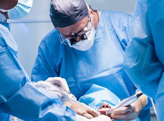 Oral surgeons in blue scrubs working on patient