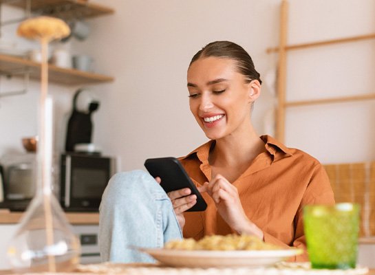 Woman smiling while looking at phone at home