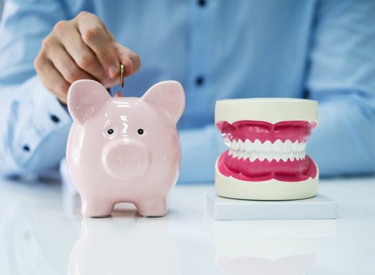 Patient in Hanover putting coins in a piggy bank for cosmetic dentistry