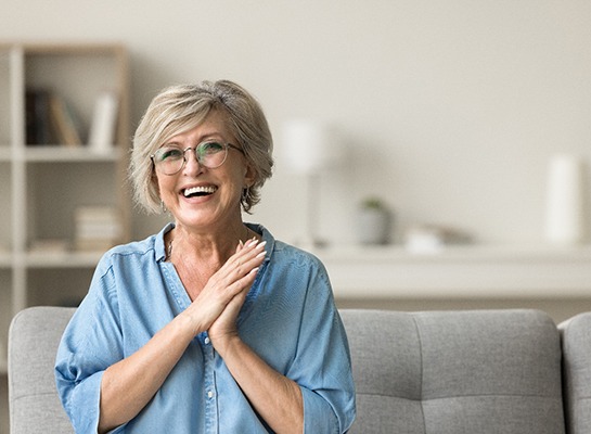 Senior woman in blue shirt smiling on couch