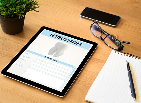 Dental insurance form on tablet next to notepad
