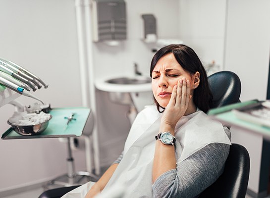 Woman with toothache sitting in treatment chair