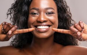 Woman pointing and smiling at her teeth after cosmetic dentistry