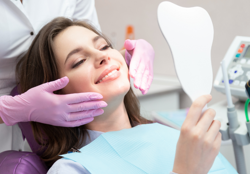 Woman smiling into mirror in dentist chair