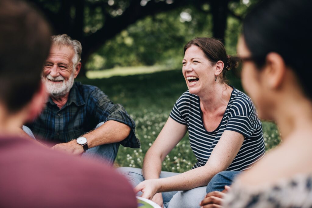 Group of adults sitting together outside talking and laughing
