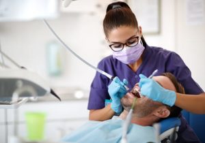 a dentist performs a dental sealants procedure on a patient in a chair
