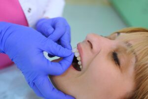 dentist shows patient the benefits of veneers by comparing veneers with patient's original teeth