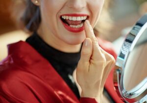 woman holding a mirror and touching her tooth where she had dental bonding