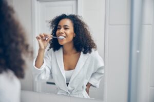 woman brushing her teeth is one way in taking care of dental implants
