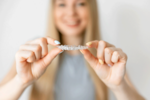 a woman holds up an invisalign clear aligner