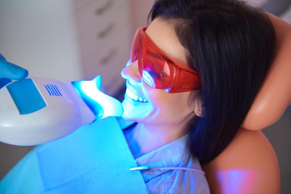 patient sits in dental exam chair and receives teeth whitening for whitening her yellow teeth