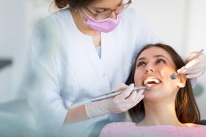 a dental professional exam a woman patients teeth and discusses restorative dentistry examples to the patient