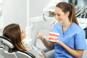 a periodontist in hanover md sits with her patient and holds a mouth model and explains periodontal treatment