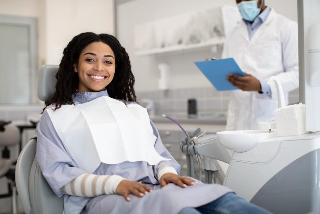 a patient smiles while sitting in a dental exam chair during one of her routine dental visits